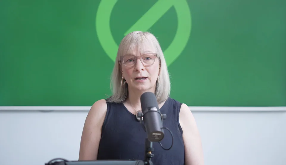 A presenter recording a course straight to camera against a branded backdrop